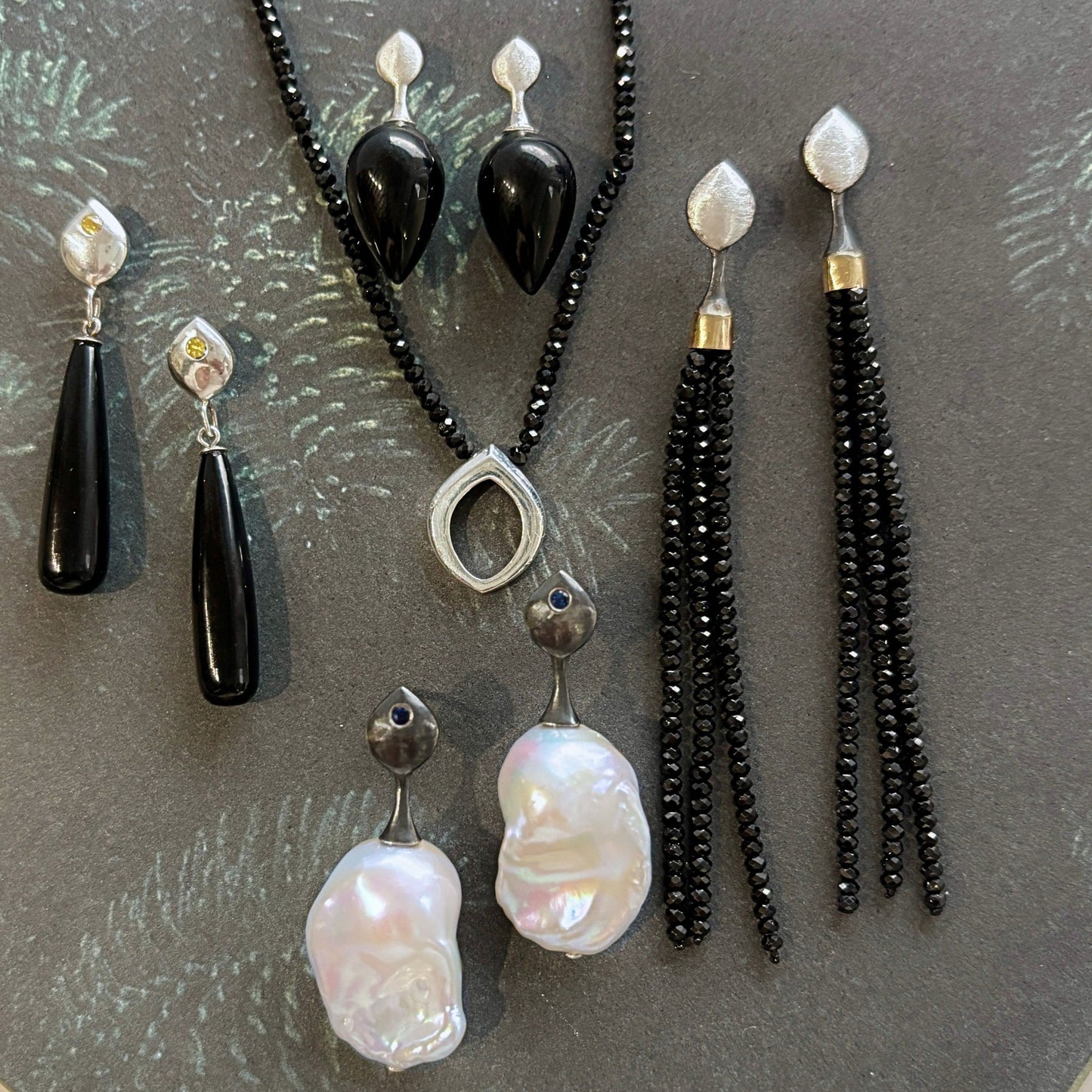 Jewelry Flat lay including necklaces and earrings in silver onyx black spinel and pearl in sterling silver and gold | ANAVIR