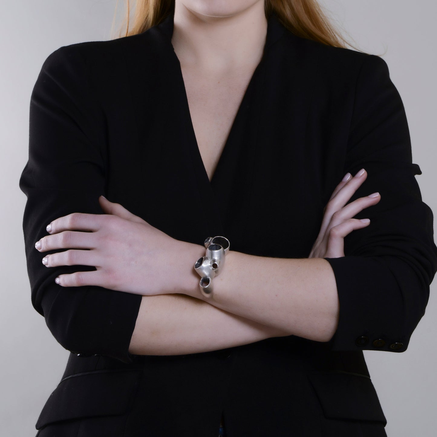model wearing a black outfit with a silver bracelet on a plain background