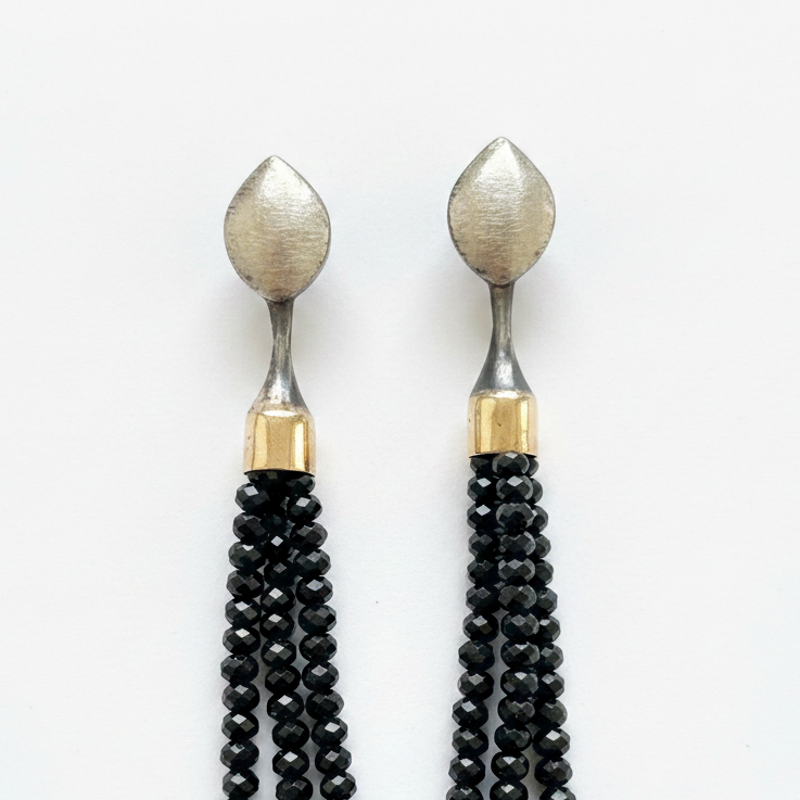 Pair of earrings with black beaded tassels on a white background