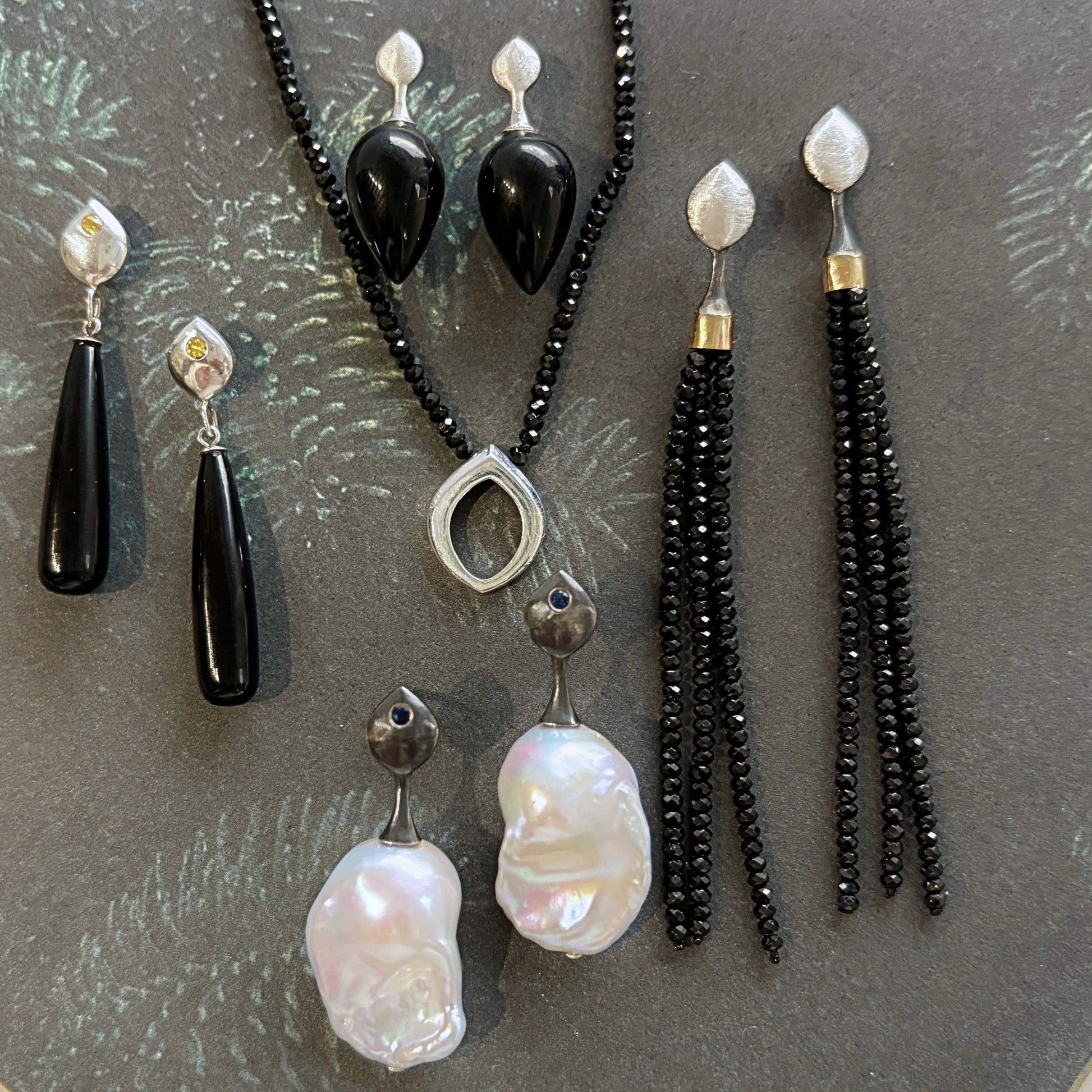 Jewelry Flat lay including necklaces and earrings in silver onyx black spinel and pearl in sterling silver and gold | ANAVIR